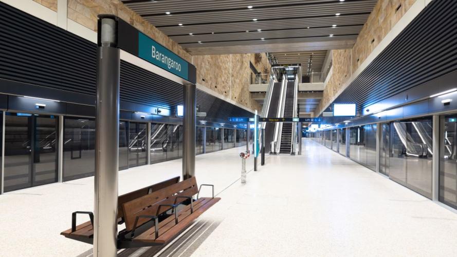 Inside of Barangaroo Station metro platform with escalators and bench for passengers opposite to the metro screen doors