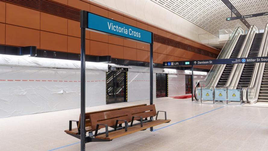 Victoria Cross Station signage above a wooden bench at the platform