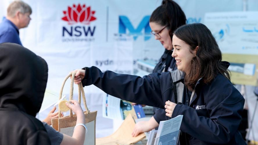 A Sydney Metro employee is handing out a bag to a stakeholder in an event