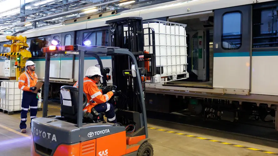 Construction worker installing a water cannister on a metro train 