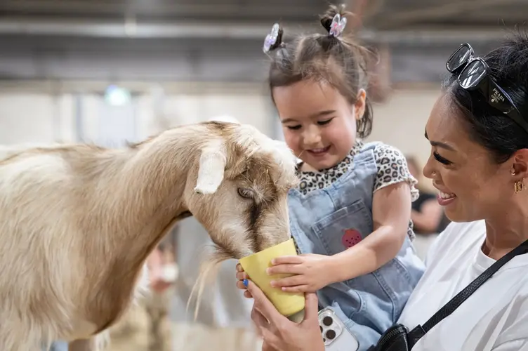 Child and mother at a farm feeding an animal
